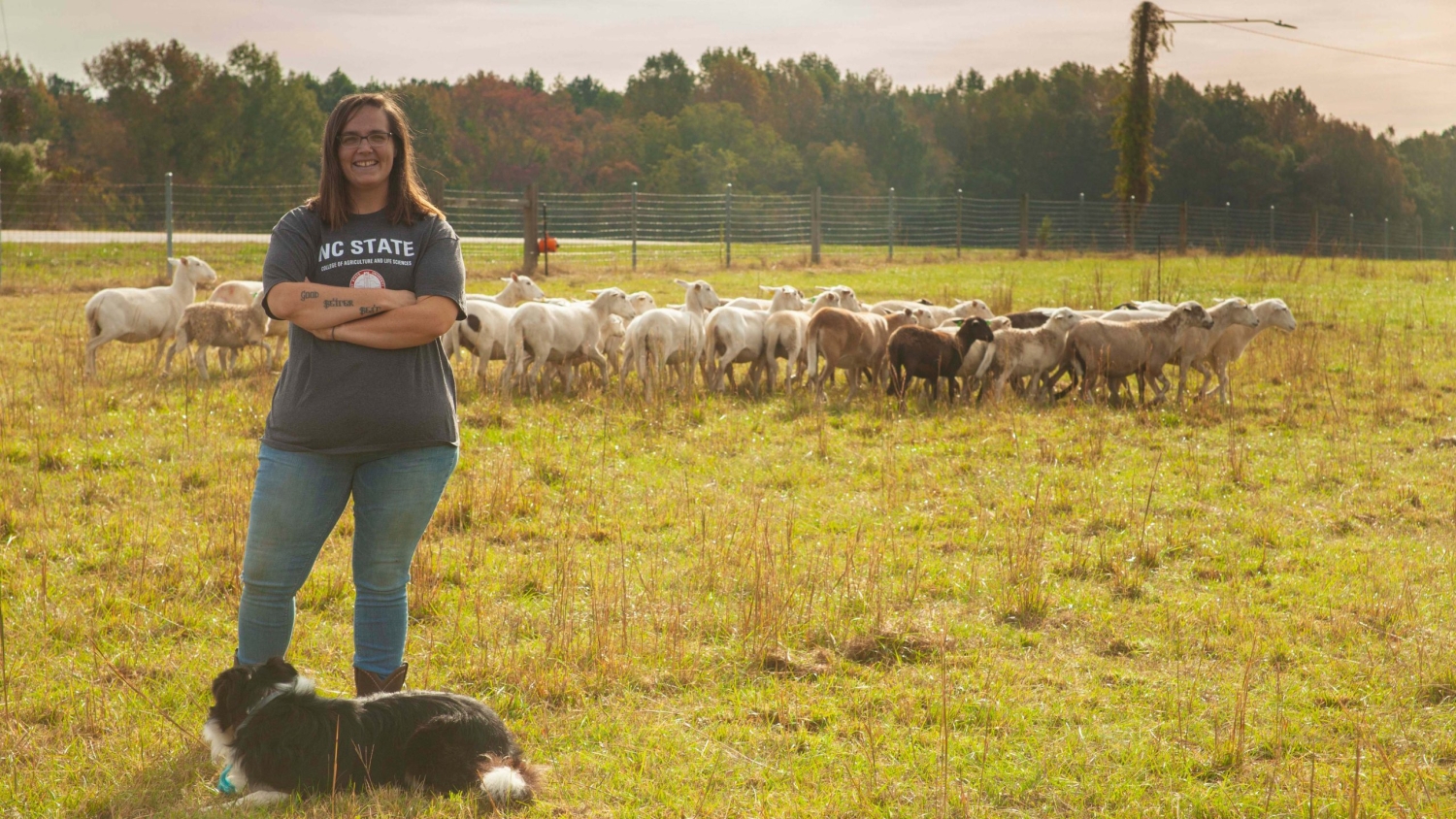 Sara Kidd stands with sheep behind her